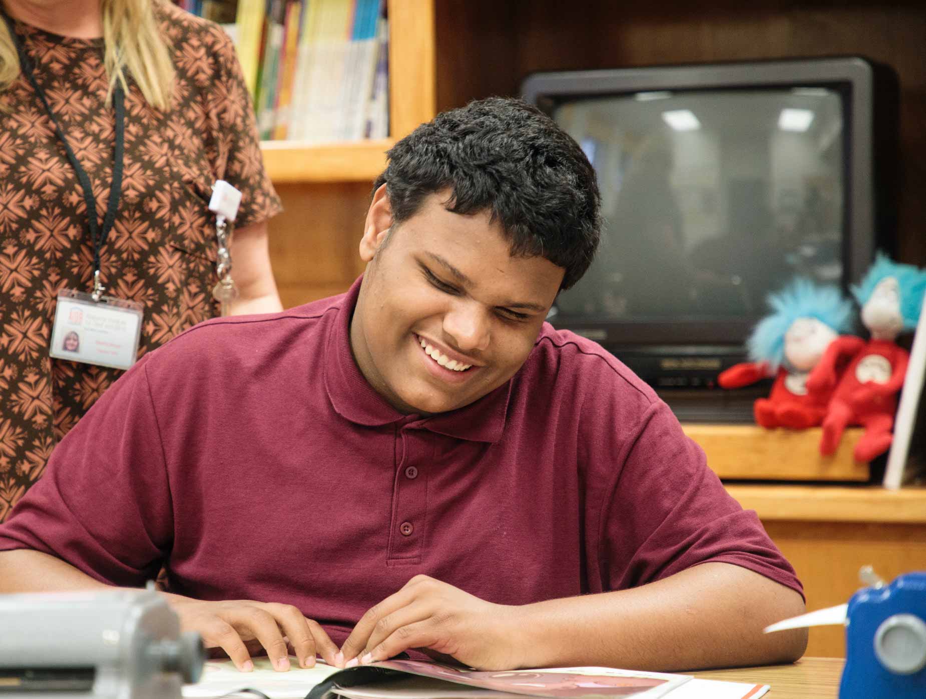 A student reading a braille book and smiling