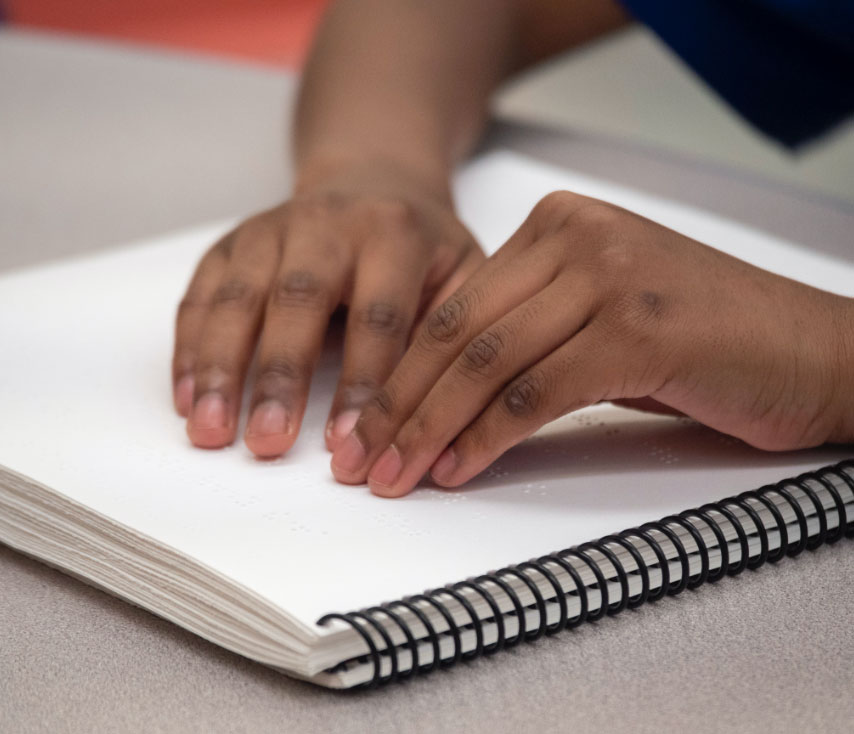 Two hands on a braille book